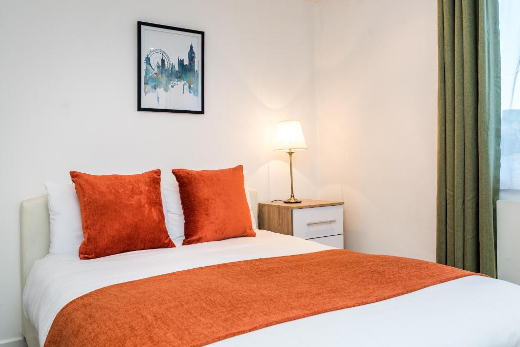 um quarto com uma cama com um cobertor laranja em City View House em Londres