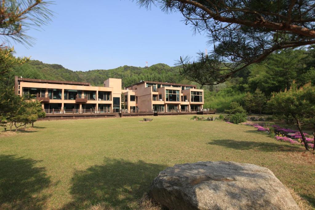 a building with a large field in front of it at Hugel Heim Pension in Pyeongchang