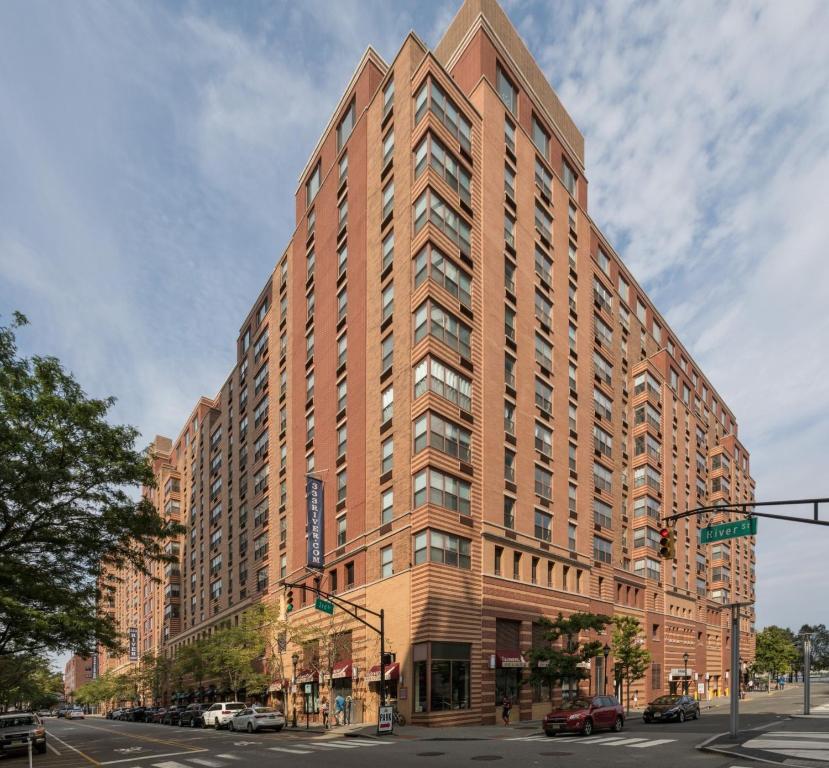 een groot bakstenen gebouw aan een stadsstraat met een verkeerslicht bij Global Luxury Suites at Hoboken Waterfront in Hoboken