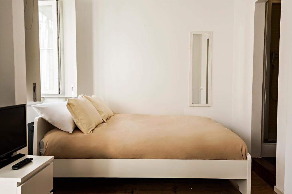 Bett in einem weißen Zimmer mit TV in der Unterkunft Apartamento ideial in Lissabon