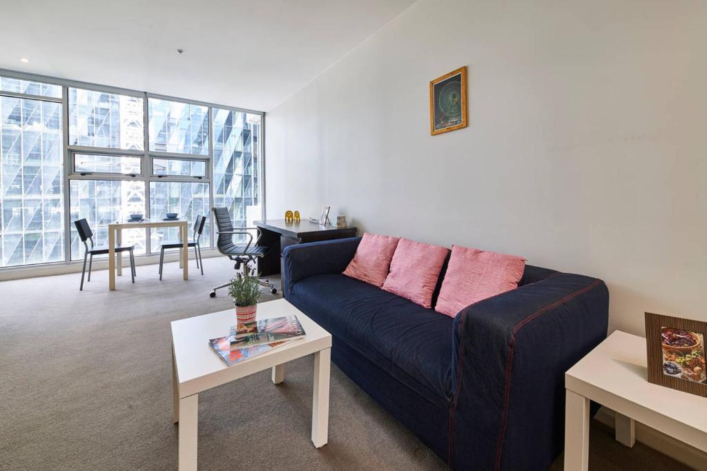 a living room with a blue couch and a table at Docklands Convenient & Modern 1 Bed Apartment in Melbourne