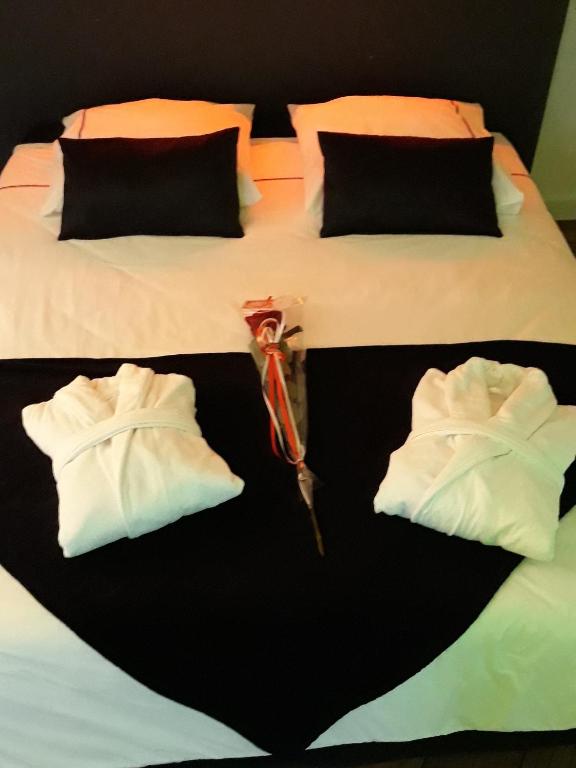a bed with three white pillows on it at La Pause Romantique in Dole