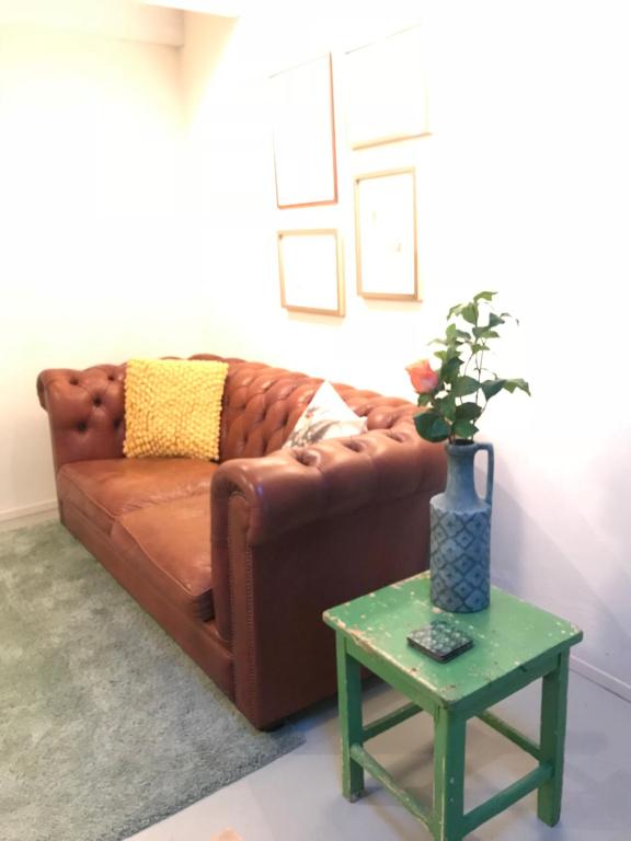 a brown couch sitting in a living room with a table at Het Huisje Breda in Breda