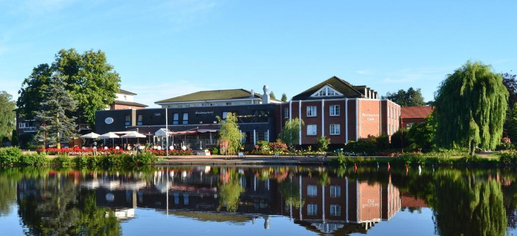 un hôtel avec un lac en face d'un bâtiment dans l'établissement PARKHOTEL - Rosarium, à Uetersen