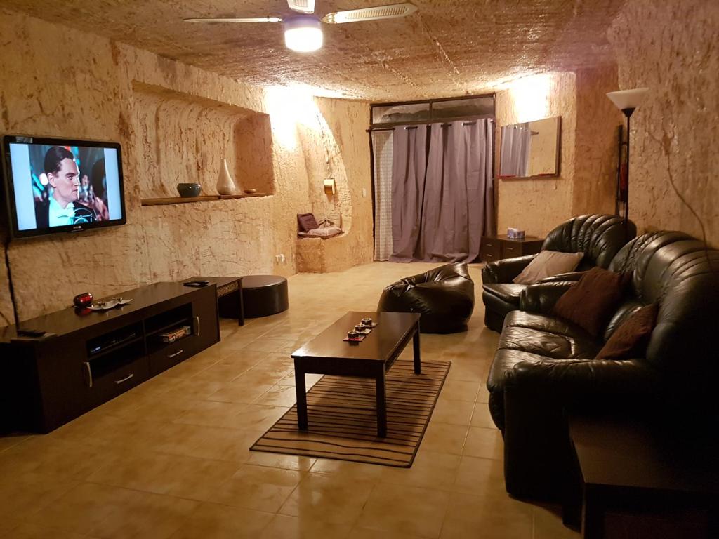 a living room with a leather couch and a tv at Underground Gem in Coober Pedy