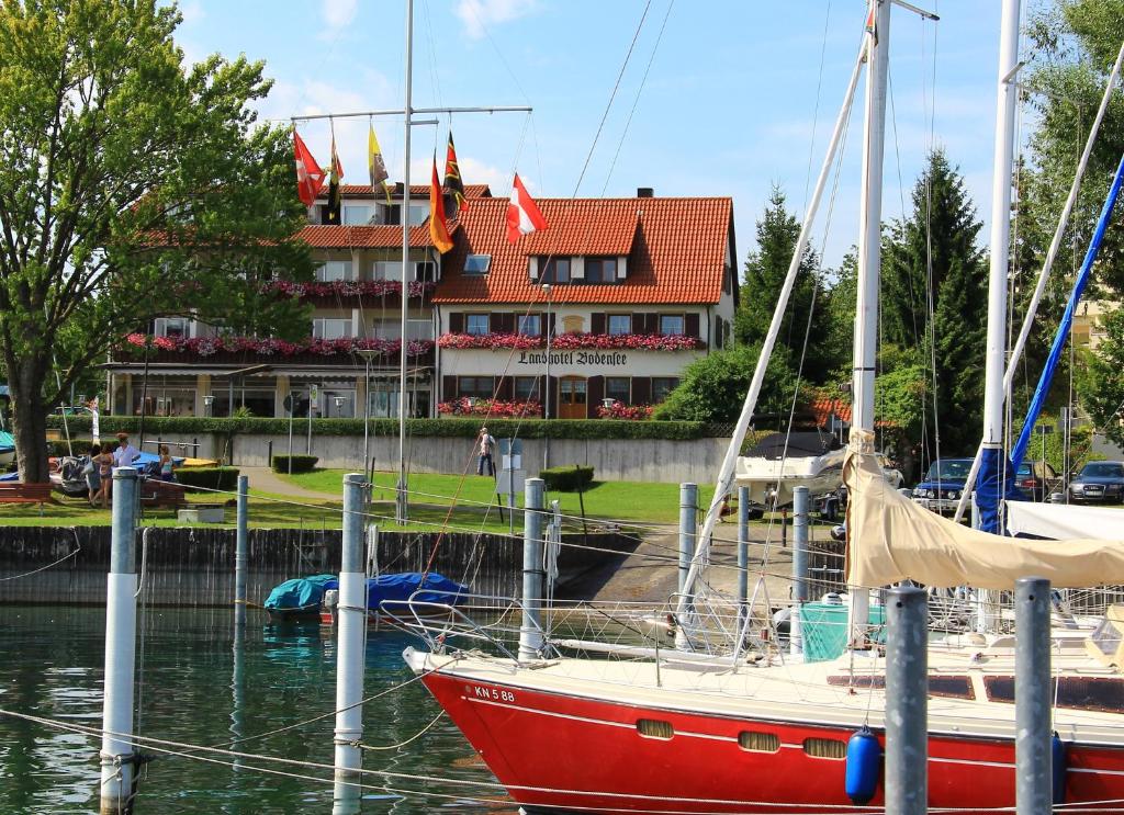 een rode boot aangemeerd in een jachthaven voor een gebouw bij Landhotel Bodensee in Konstanz