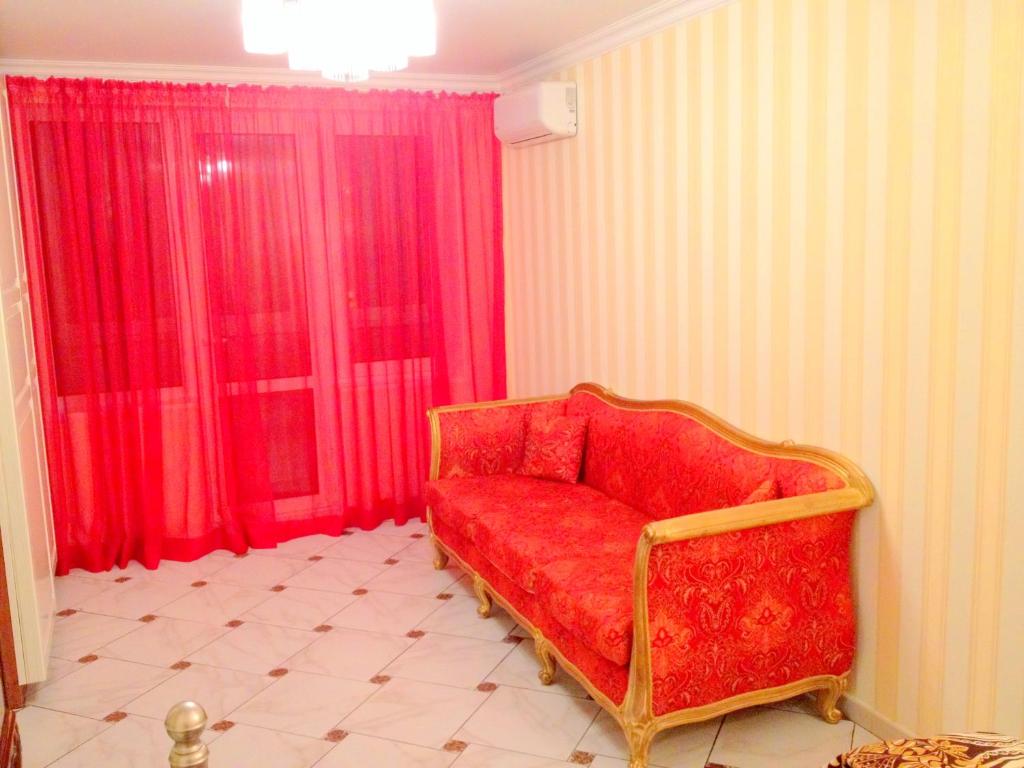 モスクワにあるСтильные апартаменты с современным ремонтомの赤いカーテン付きの部屋の赤いソファ