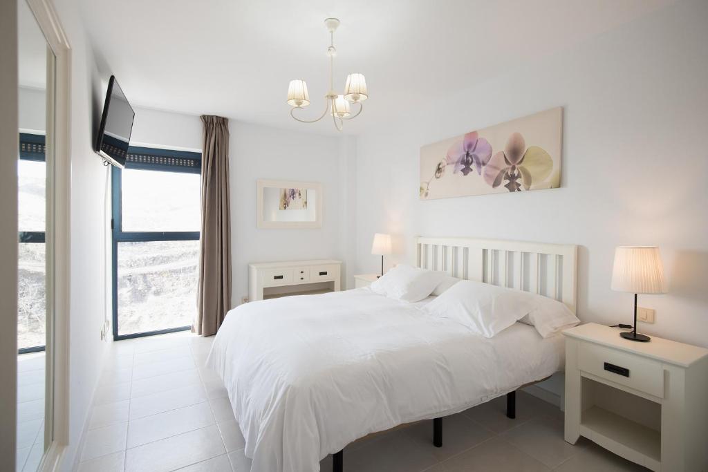 een witte slaapkamer met een bed en een raam bij Cardon Big Calm 12 in Costa Calma