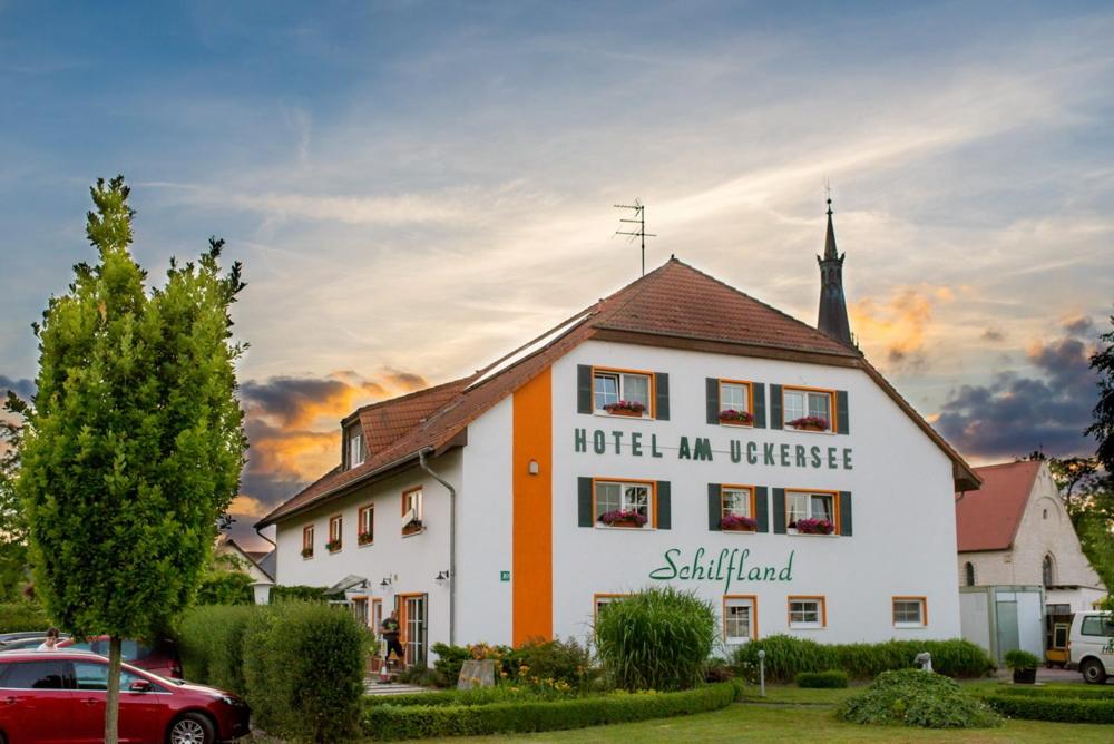 a white and orange building with a church at Hotel am Uckersee in Röpersdorf