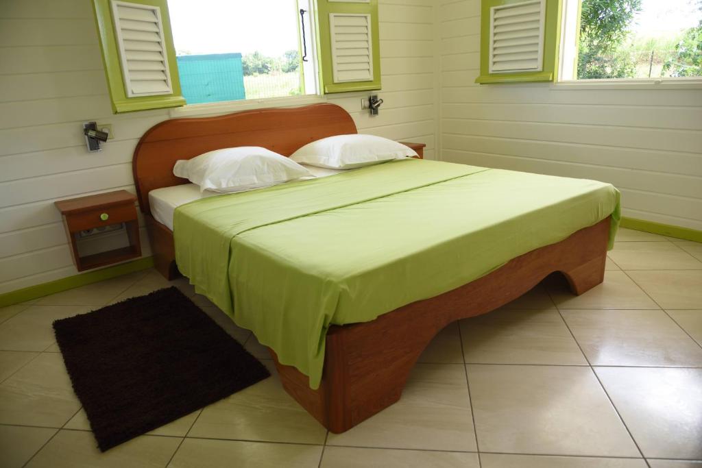 a bedroom with a large bed with a green blanket at Residence Clementine villa Douceur in Grand-Bourg