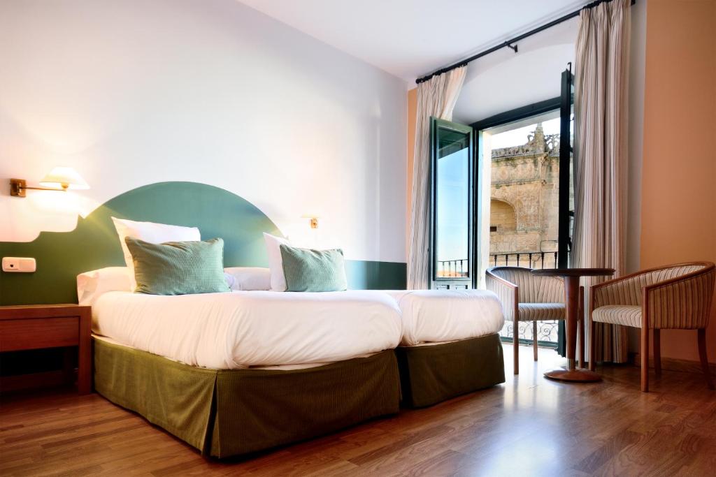 a bedroom with a large bed and a table at Hotel Ahc Palacio Coria in Coria