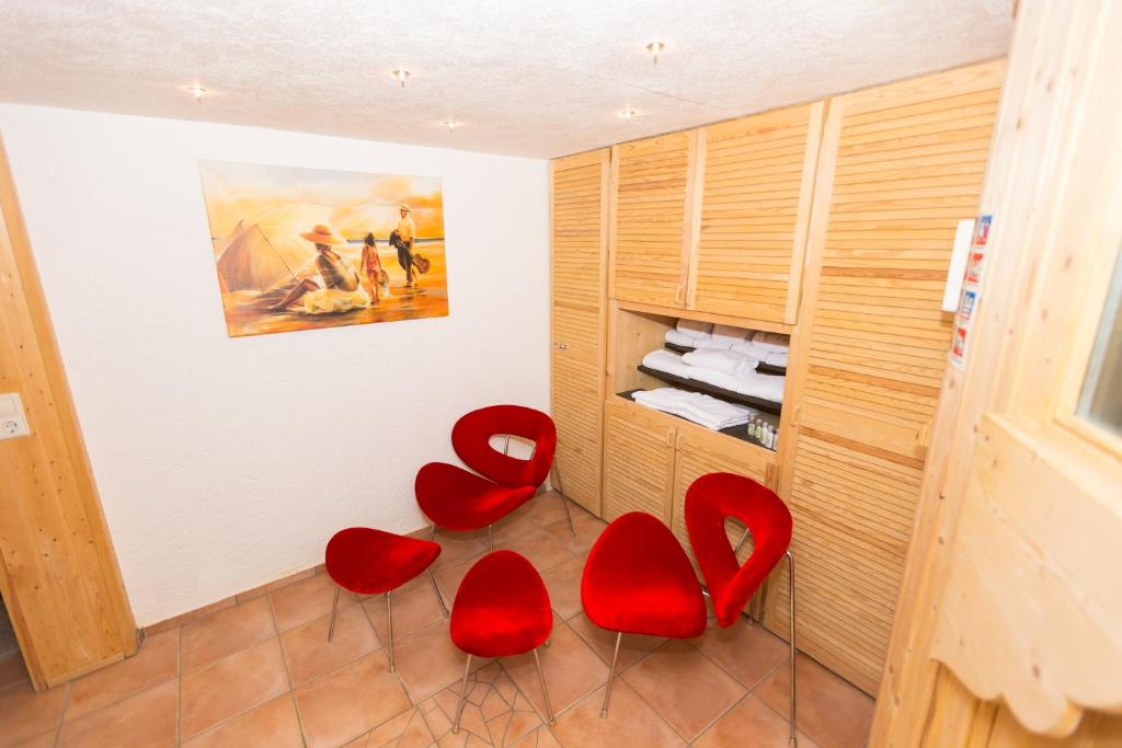 a room with two red chairs and a painting at DEVA Hotel Kaiserblick in Reit im Winkl