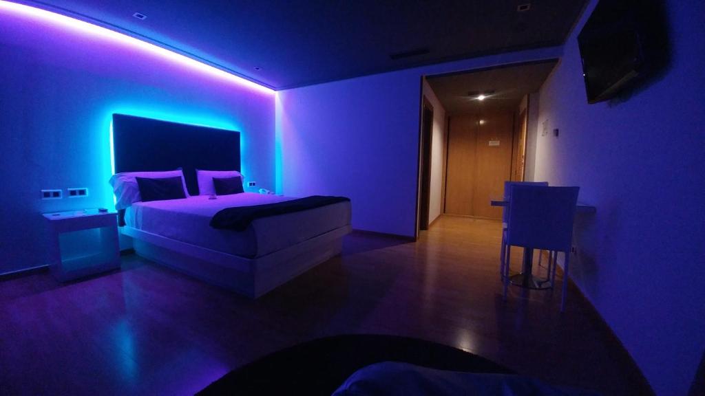 Motel Trebol في توي: غرفة نوم أرجوانية مع سرير وإضاءة أرجوانية