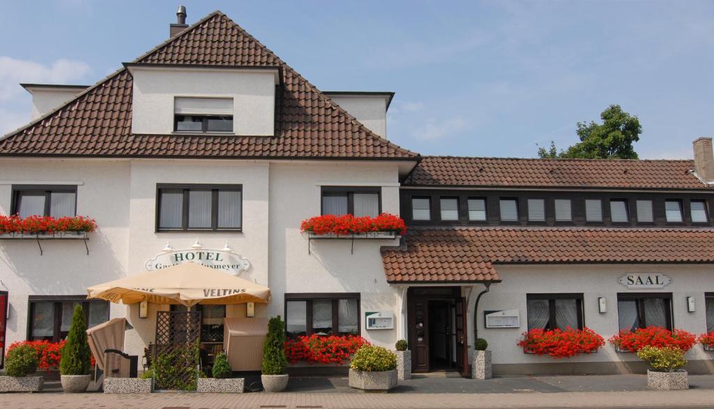 a large white building with red flowers in the windows at Hotel Gasthof Klusmeyer in Bielefeld