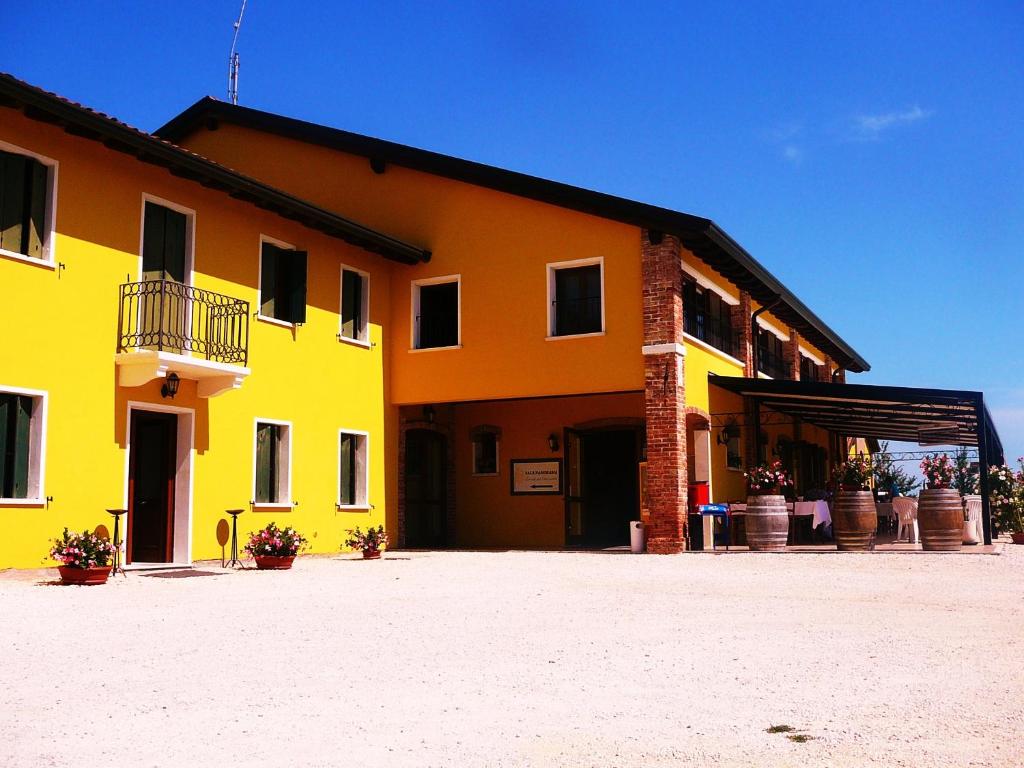 un edificio amarillo y naranja con garaje en Alloggi e Trattoria Agli Alberoni, en Brussa