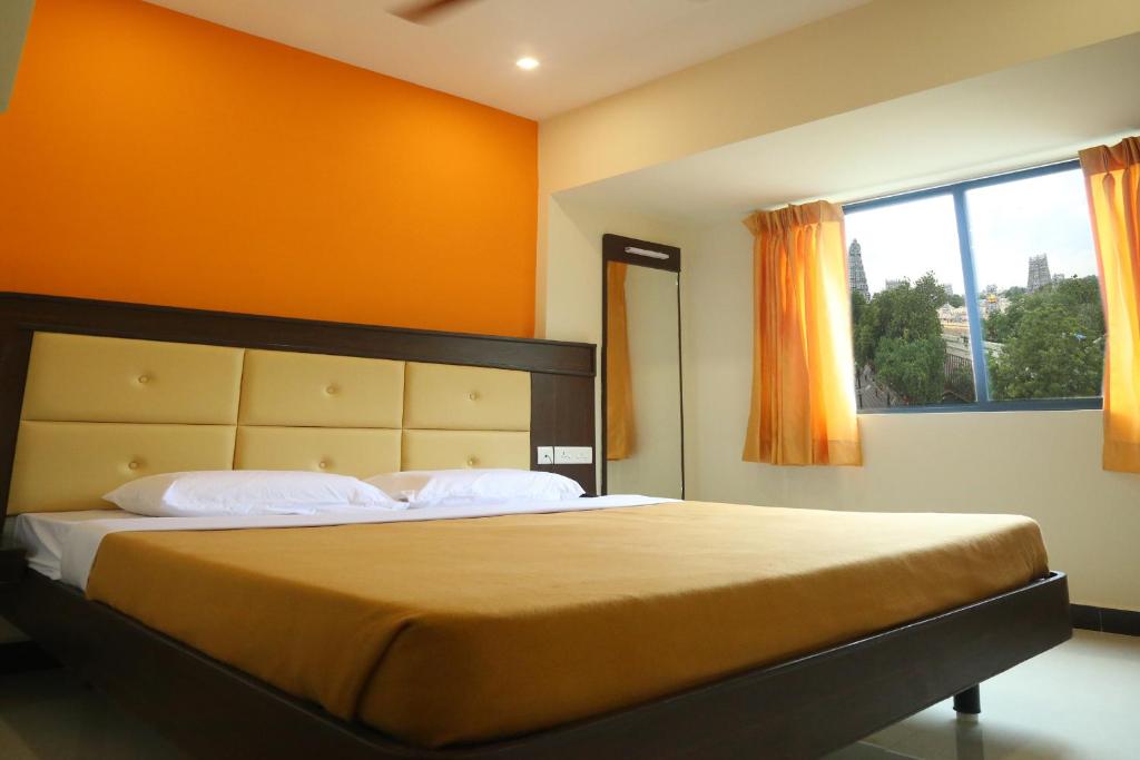 マドゥライにあるHotel Sabareesh Plazaのベッドルーム1室(オレンジ色の壁の大型ベッド1台付)