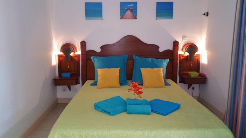 - une chambre dotée d'un grand lit avec des oreillers bleus et jaunes dans l'établissement Turquoise Caritan, à Sainte-Anne