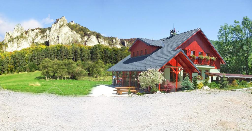 a red house with a mountain in the background at Penzión Štefánik in Súľov