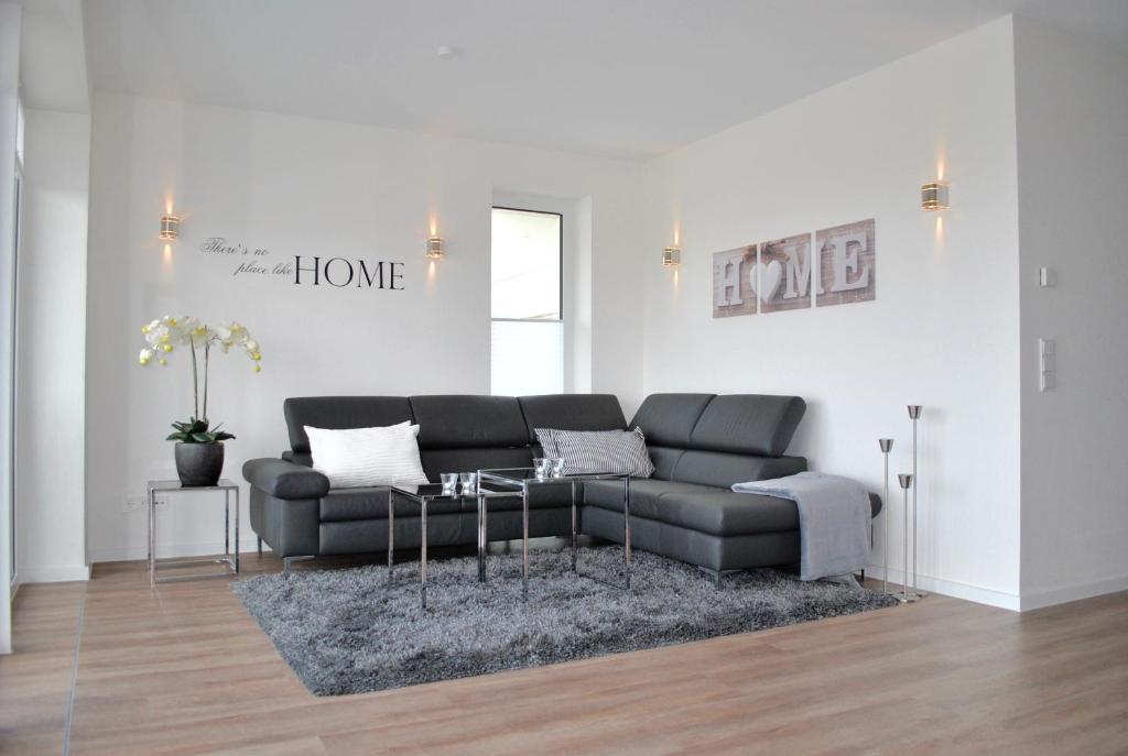 The White Pearl inkl Wäsche Set في هايليغنهافن: غرفة معيشة مع أريكة سوداء وطاولة