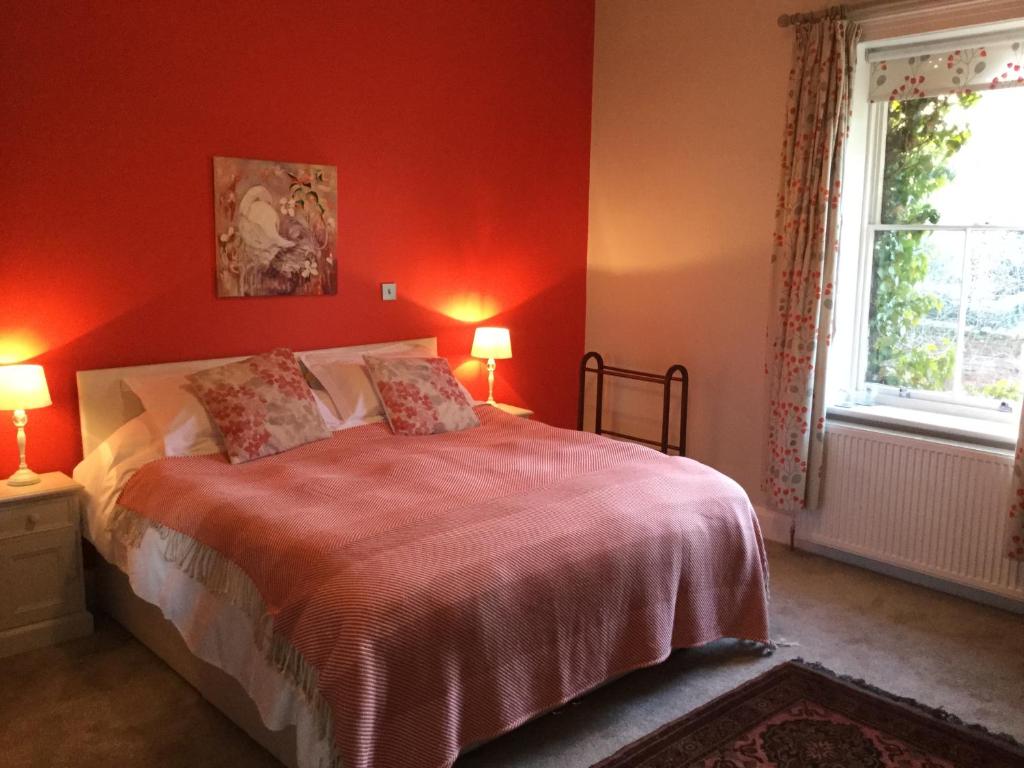 Un dormitorio con una cama con paredes rojas y una ventana en Grosmont House en Grosmont
