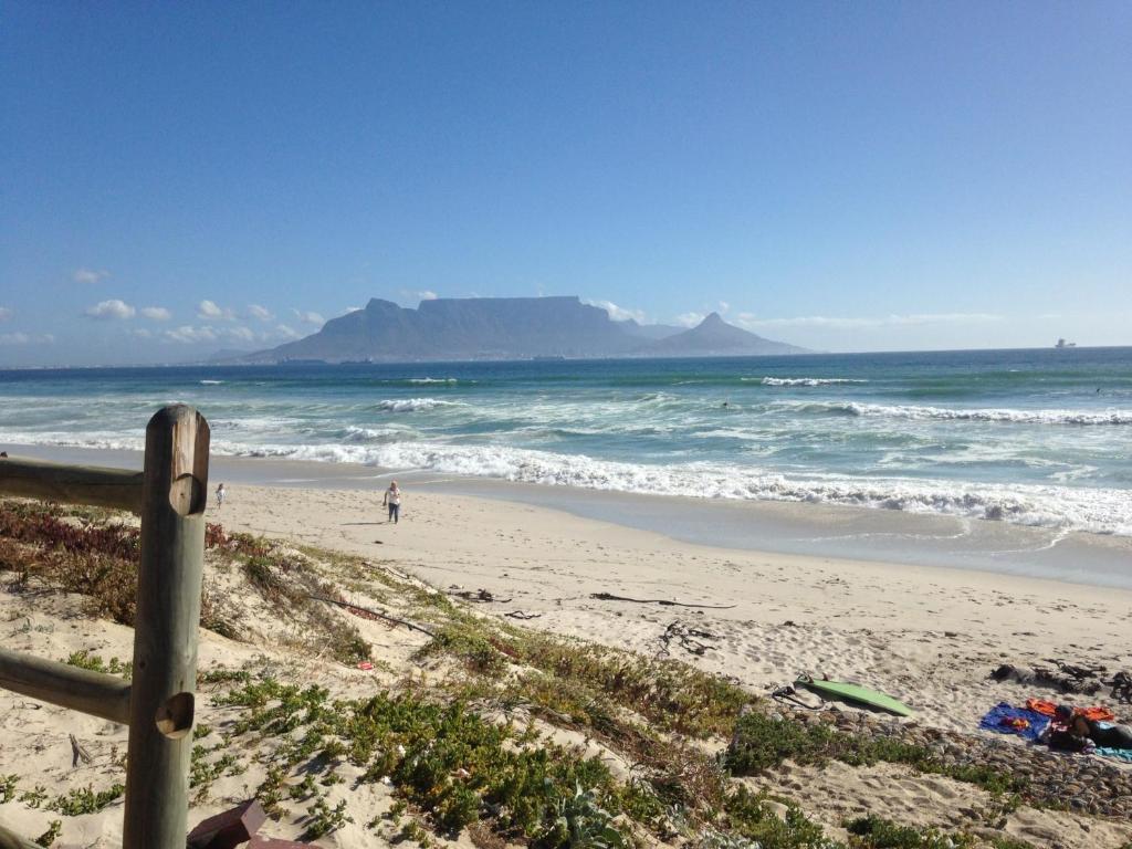 a beach with a person walking on the sand at Ocean Breeze Bloubergstrand in Bloubergstrand