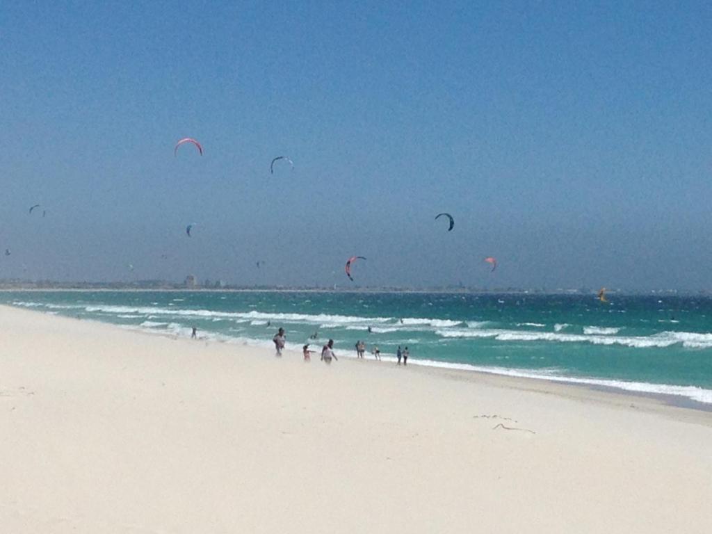 a group of people flying kites on the beach at Ocean Breeze Bloubergstrand in Bloubergstrand