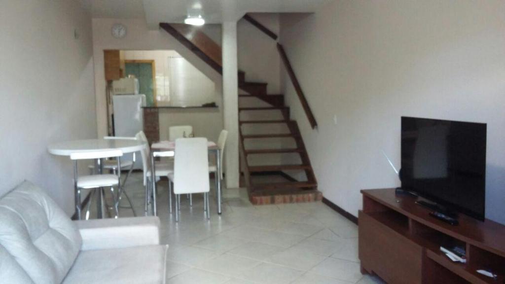 a living room with a table and a television and a staircase at Sobrado EXPRESS - Santa Cruz do Sul! in Santa Cruz do Sul