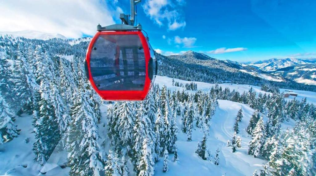 a red ski lift flying over a snow covered mountain at Apartment 408 in Orbi Palace in Bakuriani