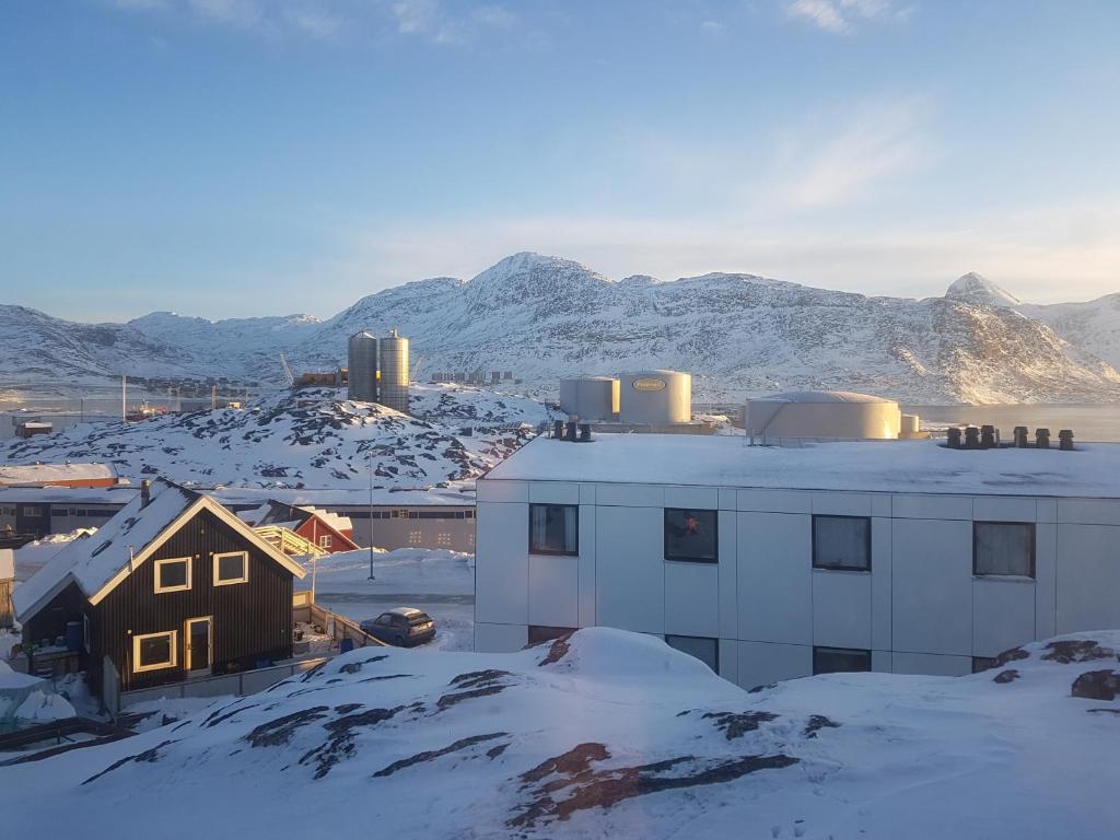 um edifício na neve com montanhas ao fundo em Vandrehuset 2 og 3 em Nuuk