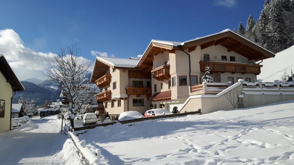 una casa en la nieve con coches aparcados en Apartment Bachmann, en Oberau