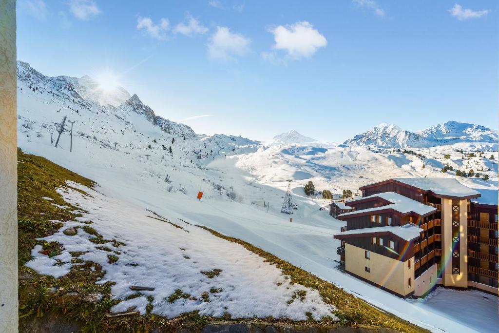 un bâtiment sur une montagne enneigée avec une piste de ski dans l'établissement Residence Les Nereides - maeva Home, à Belle Plagne