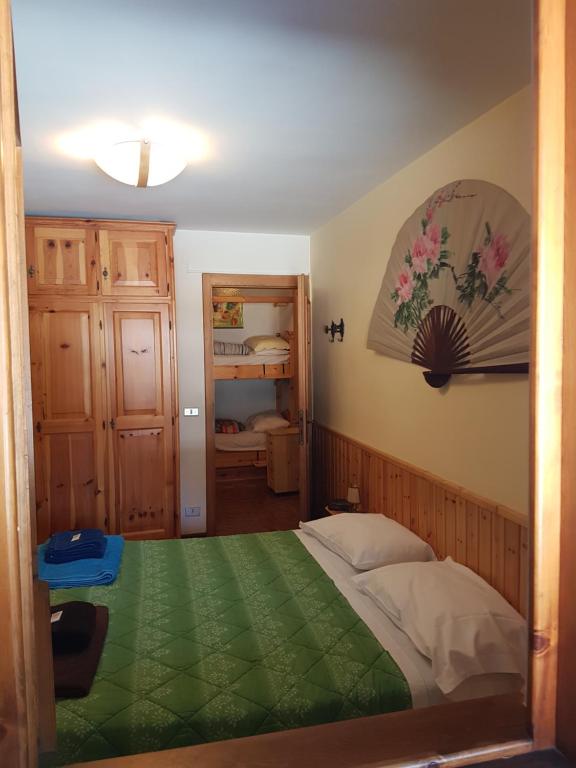 a bedroom with a bed with a green blanket at Appartamento Borgo Rio Muri in Auronzo di Cadore
