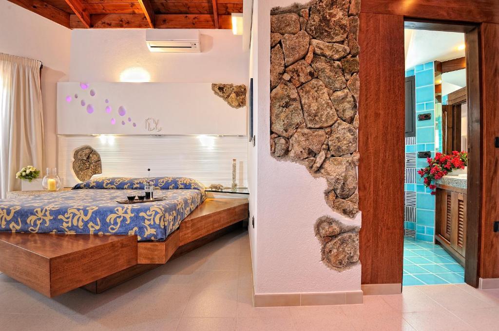 1 dormitorio con cama y pared de piedra en Residence L'Ea di Lavru - Appartamenti Mono-Bilo-Trilocali, en Porto San Paolo