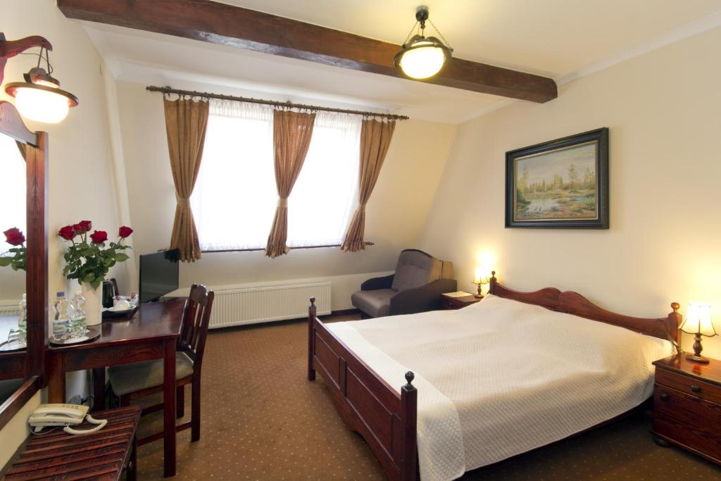 um quarto com uma cama, uma secretária e uma cadeira em Hotel Retman em Toruń