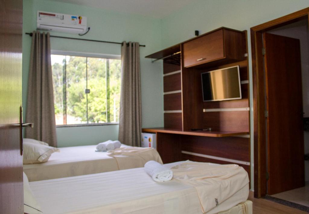 um quarto de hotel com duas camas e uma televisão em Pousada Monte Oliveira em Aparecida