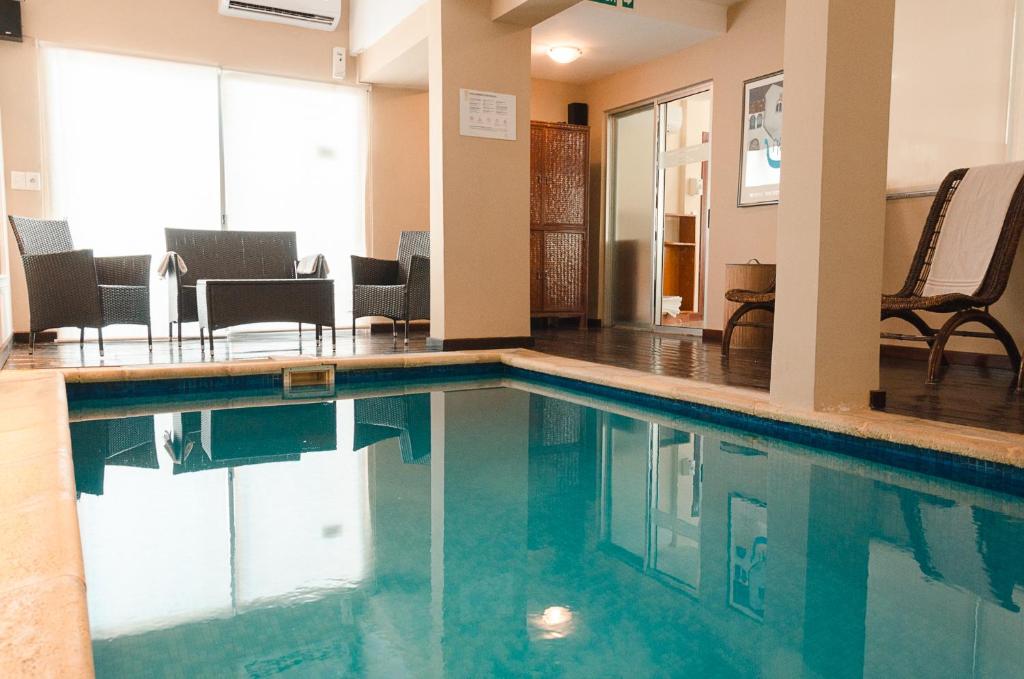 a swimming pool in a hotel with chairs and tables at Hotel Sunset Beach in Punta del Este