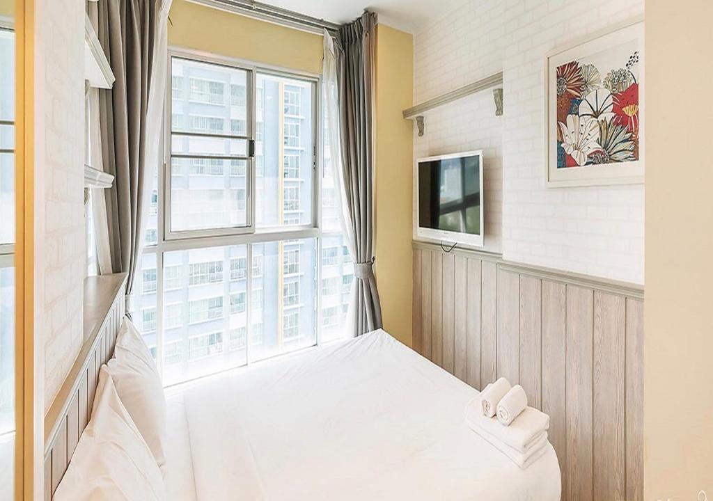 a small room with a bed and a window at Lumpini Parkbeach Pattaya Pool View in Jomtien Beach