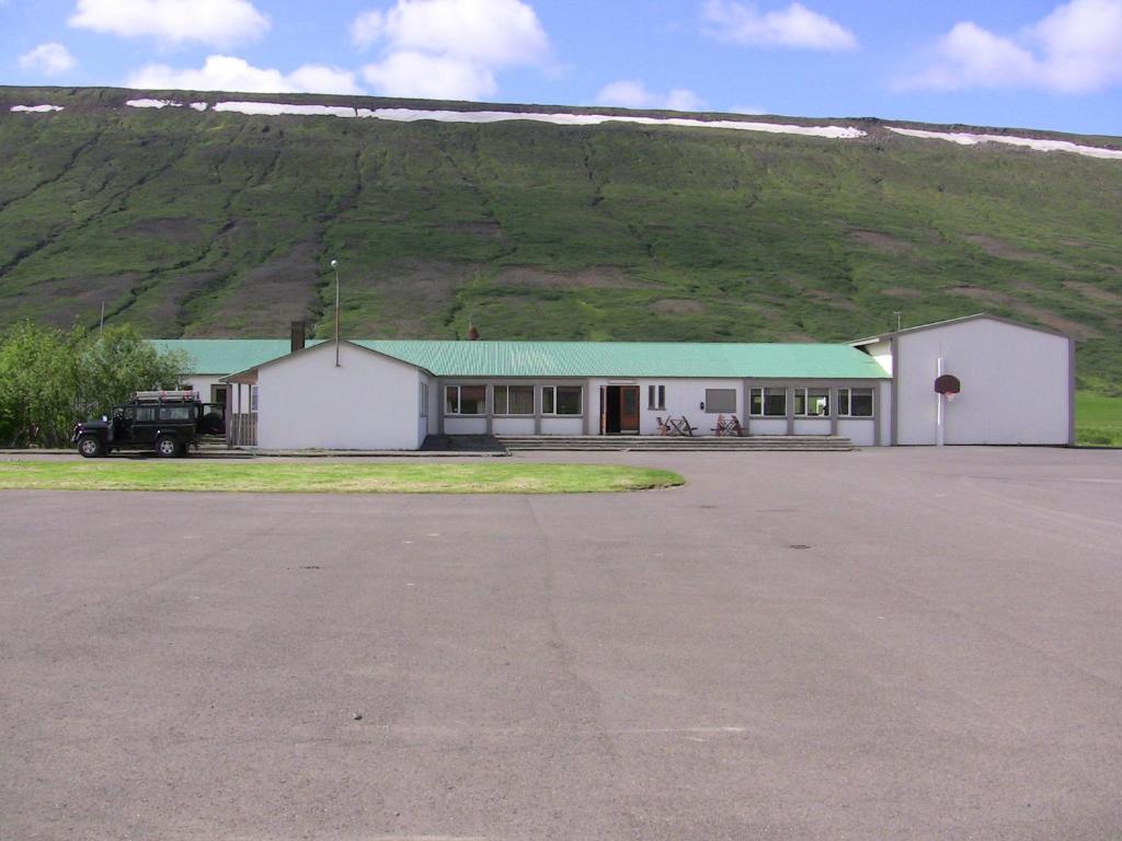 un edificio blanco con techo verde frente a una colina en Kidagil Guesthouse en Kiðagil