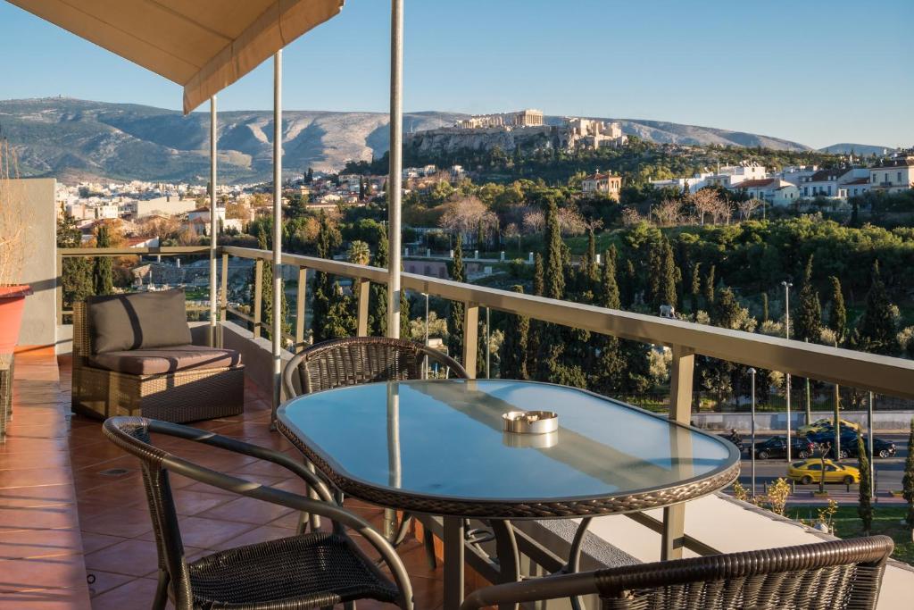een tafel en stoelen op een balkon met uitzicht bij Virgo - Loft with Spectacular View to Acropolis in Athene