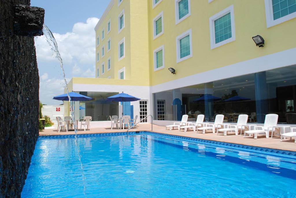 ポサ・リカ・デ・イダルゴにあるRio Vista Inn Business High Class Hotel Poza Ricaのホテル正面のプール(椅子、パラソル付)