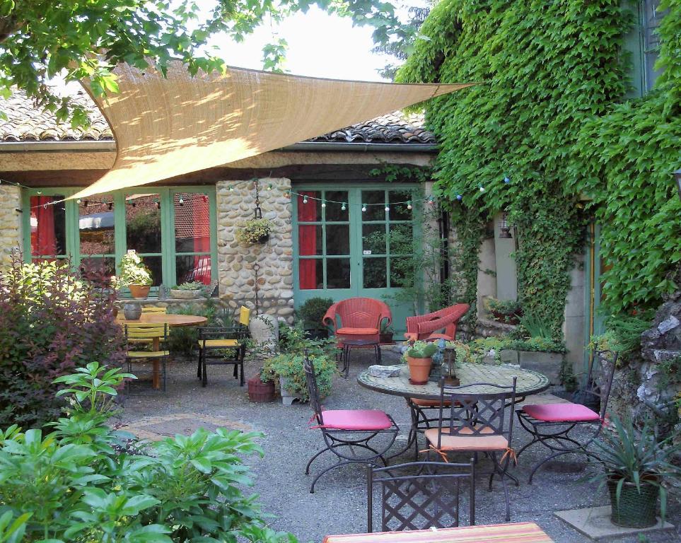 a patio with tables and chairs in a garden at L'Auberge des Collines in Granges-Les-Beaumont