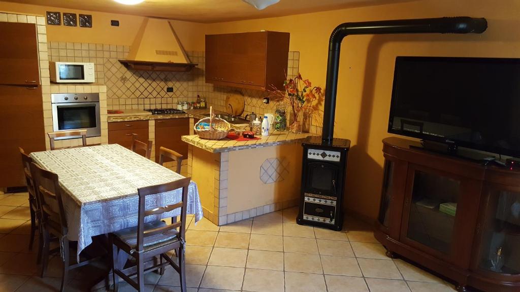 een keuken met een tafel en een televisie en een keuken met een tafel en stoelen bij Michela in Monteforte dʼAlpone