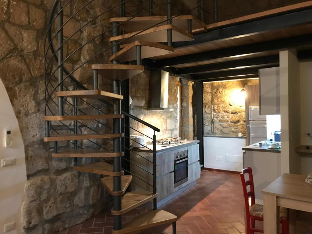 a spiral staircase in a kitchen with a stone wall at Palazzo Urbani in Orvieto