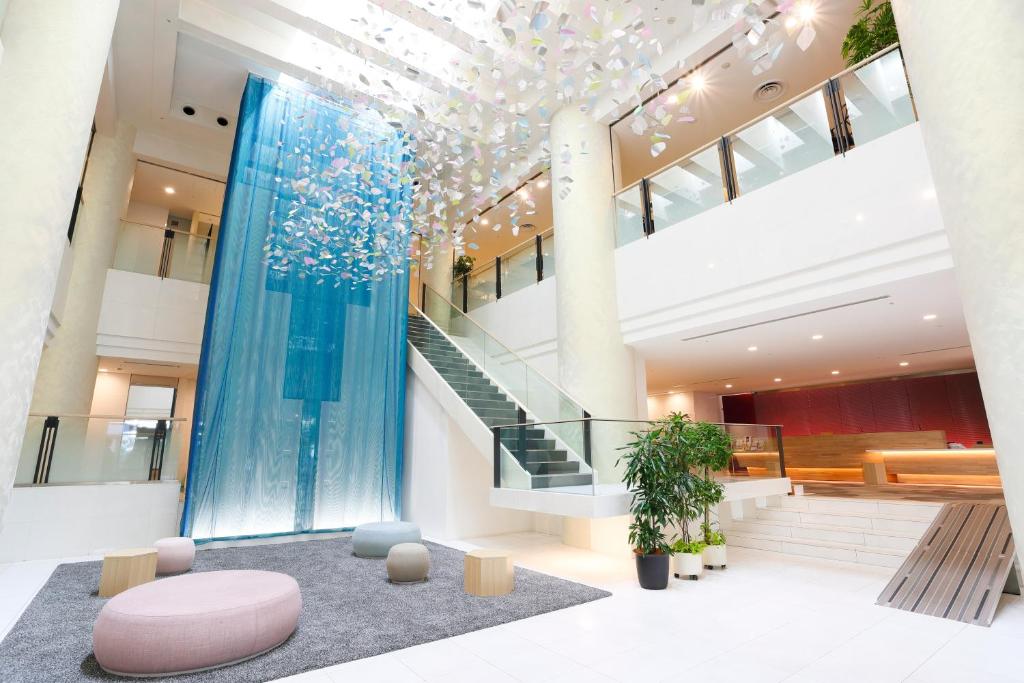 a lobby of a building with a staircase and a pink stool at Tenza Hotel & SKYSPA at Sapporo Central in Sapporo