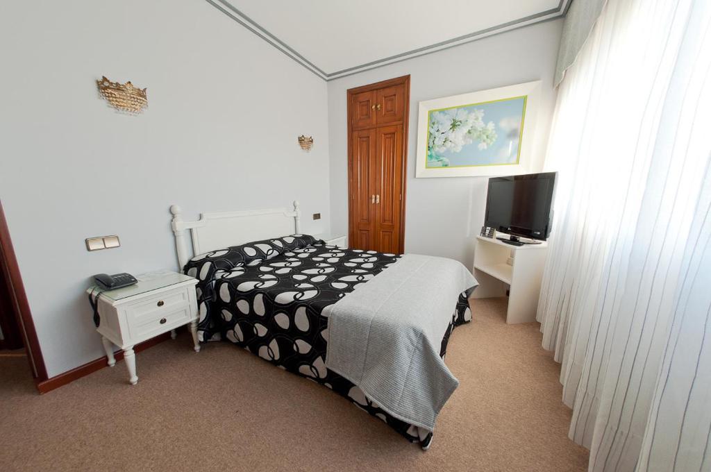 a bedroom with a black and white bed and a tv at Hotel Don Pepe in Poio