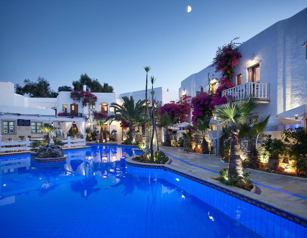 a large swimming pool with palm trees and buildings at Polikandia Hotel in Chora Folegandros