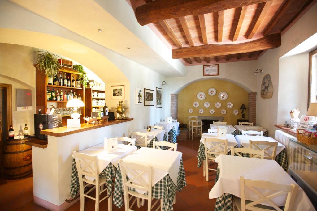 restauracja z białymi stołami i krzesłami oraz bar w obiekcie Il Casale Del Cotone w mieście San Gimignano