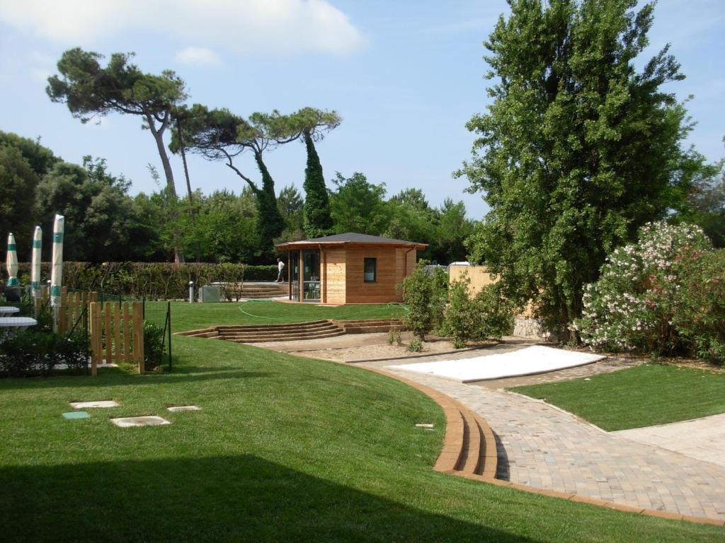 un jardin avec une petite cabine en arrière-plan dans l'établissement Miramare Resort, à Tirrenia