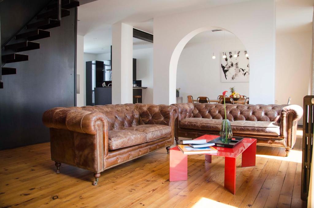 een woonkamer met een bruine leren bank en een tafel bij La Casa Cosy, Appart'Hôtel in Biarritz