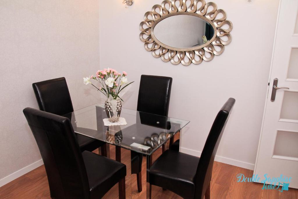 stół jadalny z czarnymi krzesłami i lustrem w obiekcie Apartment Double Sapphire Time w Łodzi
